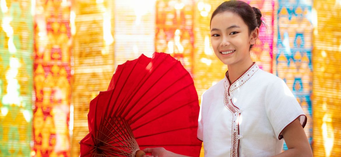 Asian girl in northern traditional costume and red umbrella stand in temple