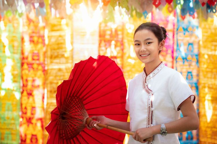 Asian girl in northern traditional costume and red umbrella stand in temple