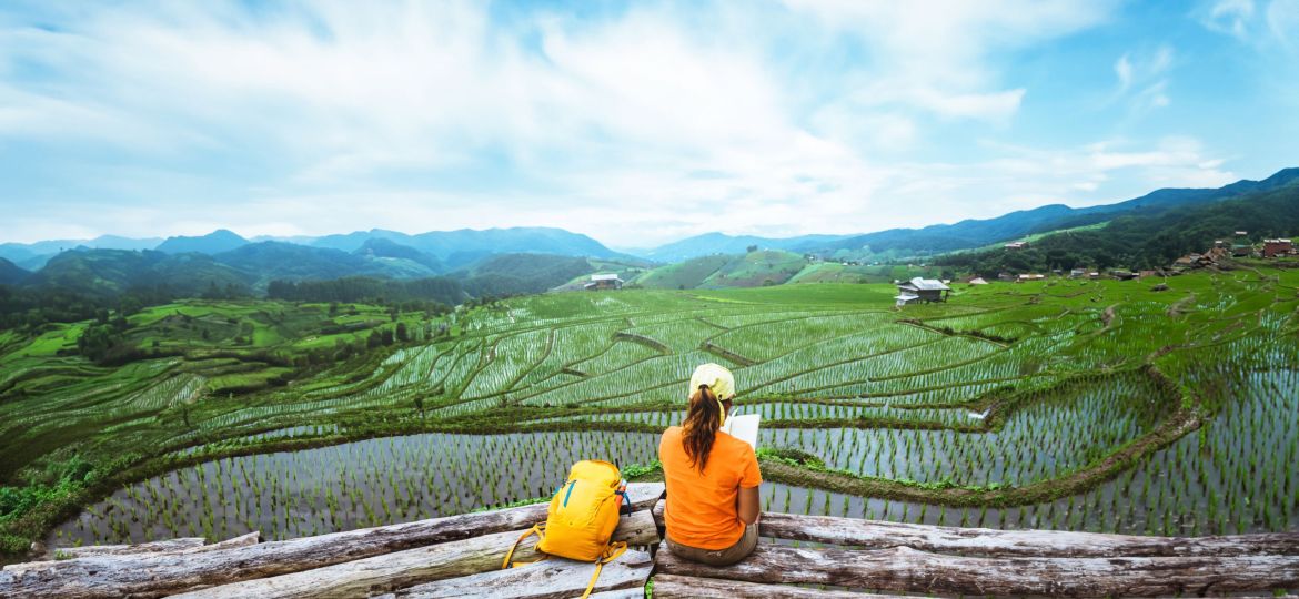 Asian woman travel nature. Travel relax. Standing reading book the balcony of the resort. View of the field on the Moutain in summer. Thailand