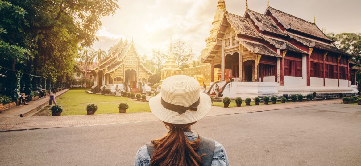 Female tourist looking to the beautiful view of Wat Phra Singh in Chiang Mai, Thailand at sunset.