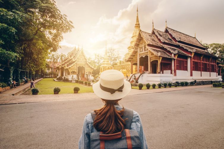 Female tourist looking to the beautiful view of Wat Phra Singh in Chiang Mai, Thailand at sunset.