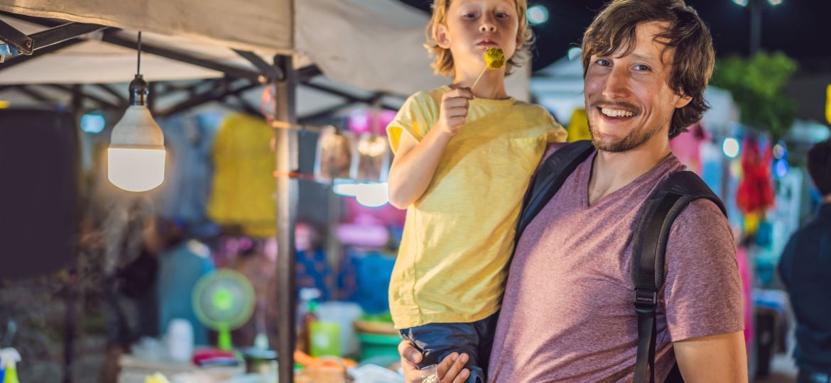 Dad and son are tourists on Walking street Asian food market